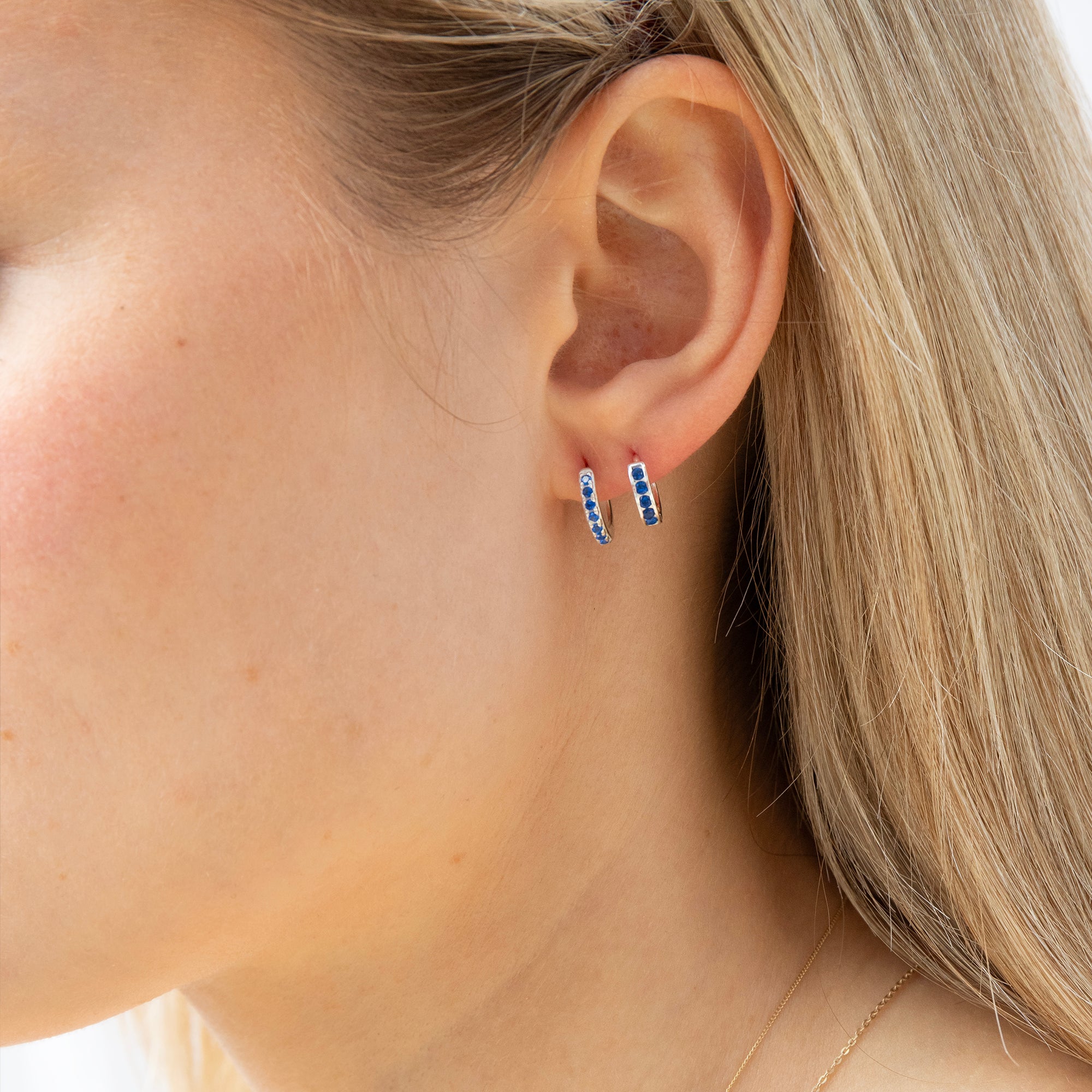Close-up of an ear wearing blue hoop earrings with blonde hair - seolgold