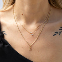 Gold necklace with a letter 'h' pendant on a person wearing a black top - seolgold
