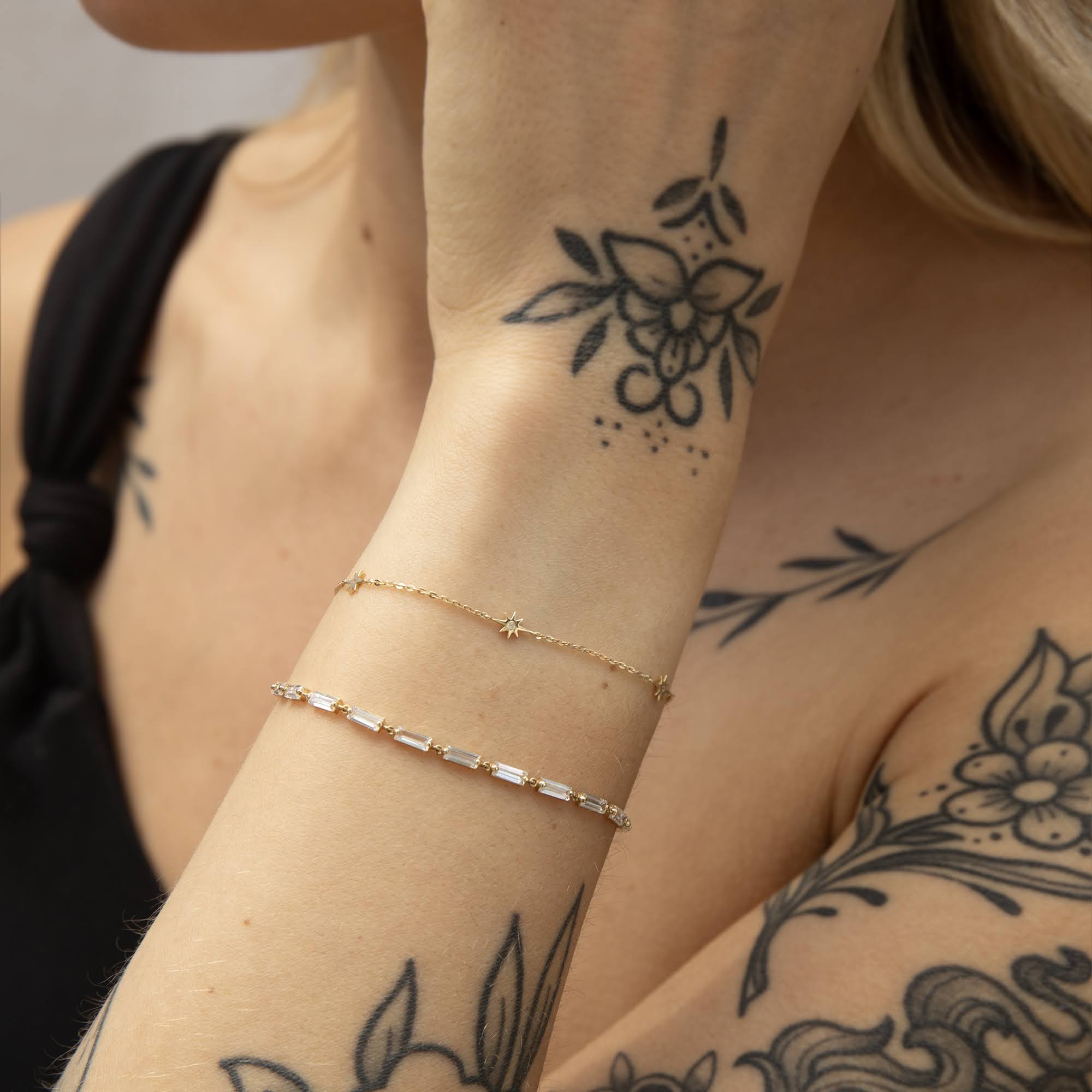 Close-up of a person's arm with gold bracelets and tattoos - seolgold
