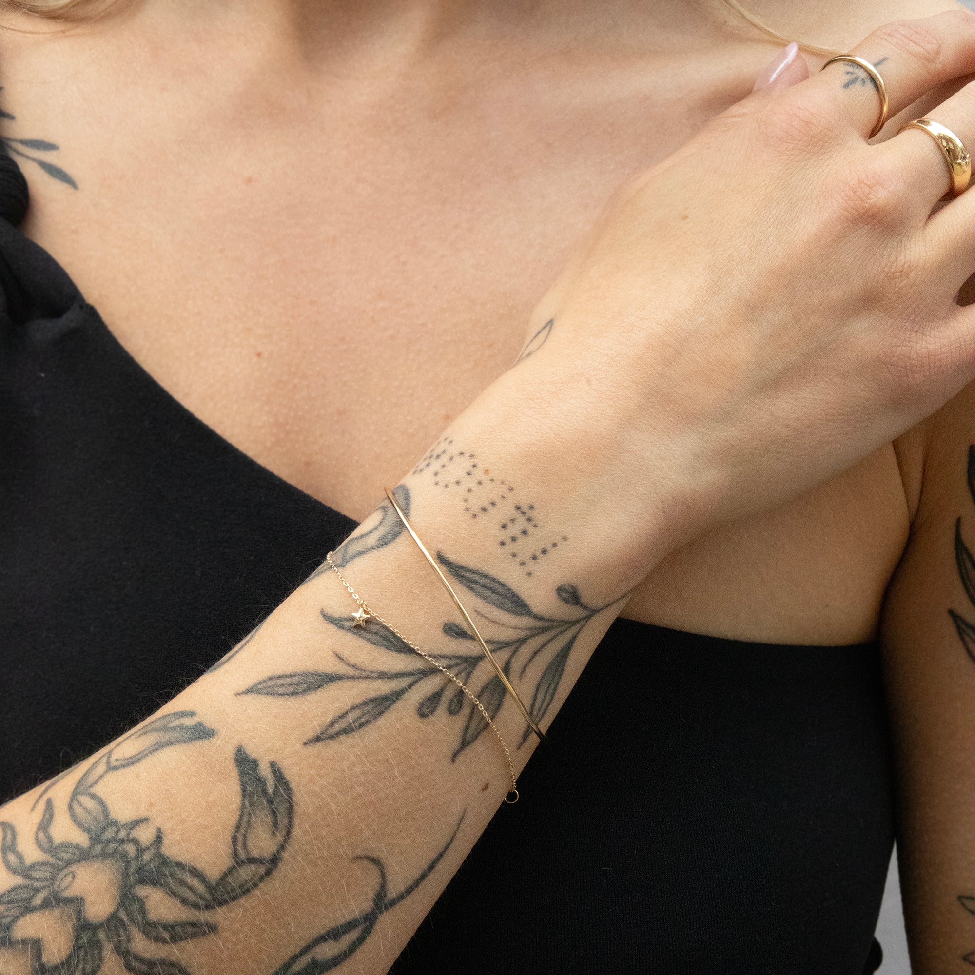 Person with tattoos on arm wearing a gold bracelet and ring - seolgold