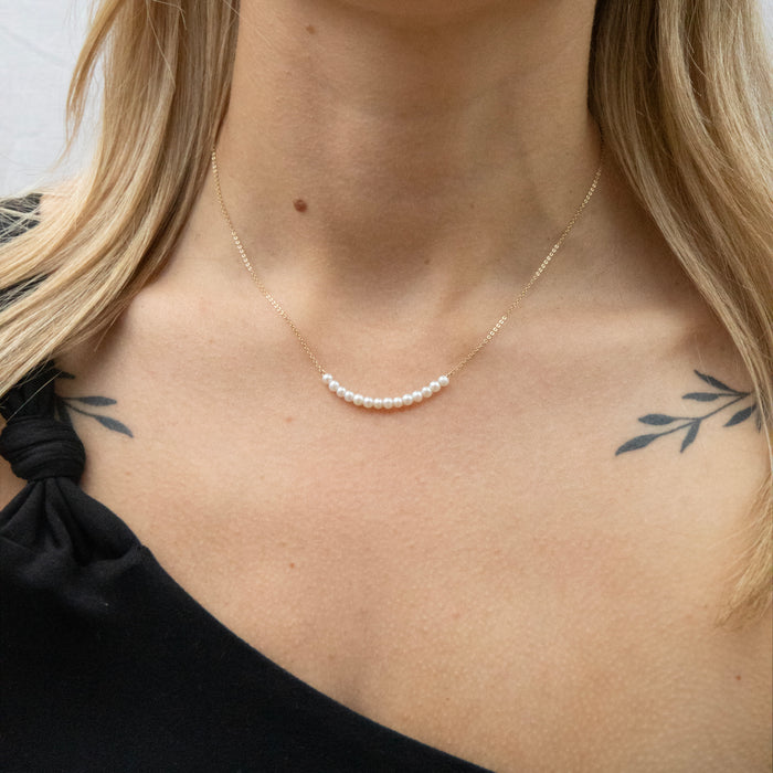 Pearl necklace worn by a person with tattoos on their shoulders - seolgold
