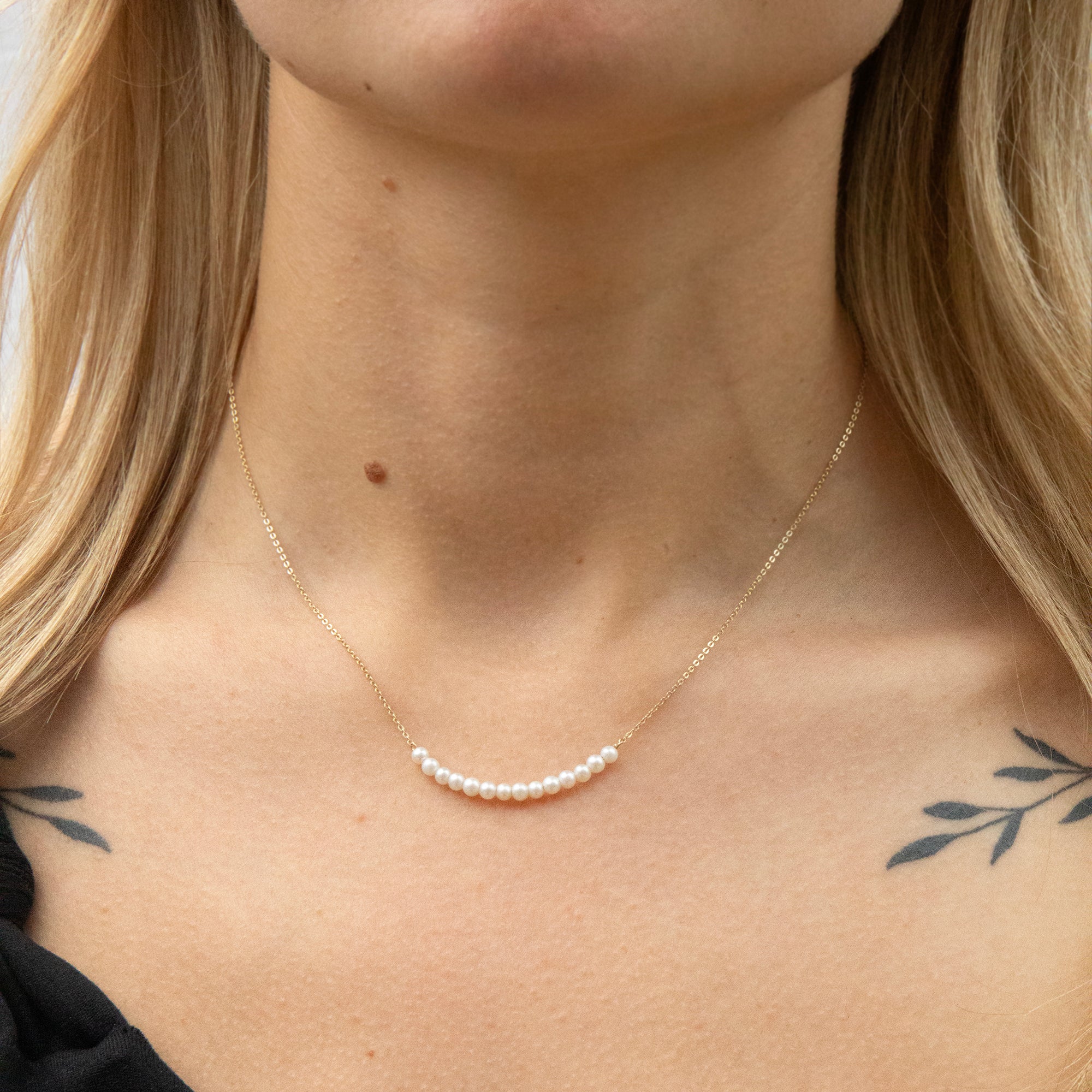 Pearl necklace on a person with tattoos visible on the skin - seolgold