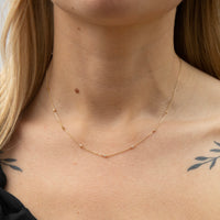 Close-up of a person wearing a delicate gold necklace with a blurred background - seolgold