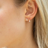 Close-up of an ear wearing a pair of pearl earrings with blonde hair partially visible - seolgold