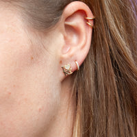 Close-up of an ear wearing gold hoop earrings with a blurred background - seolgold