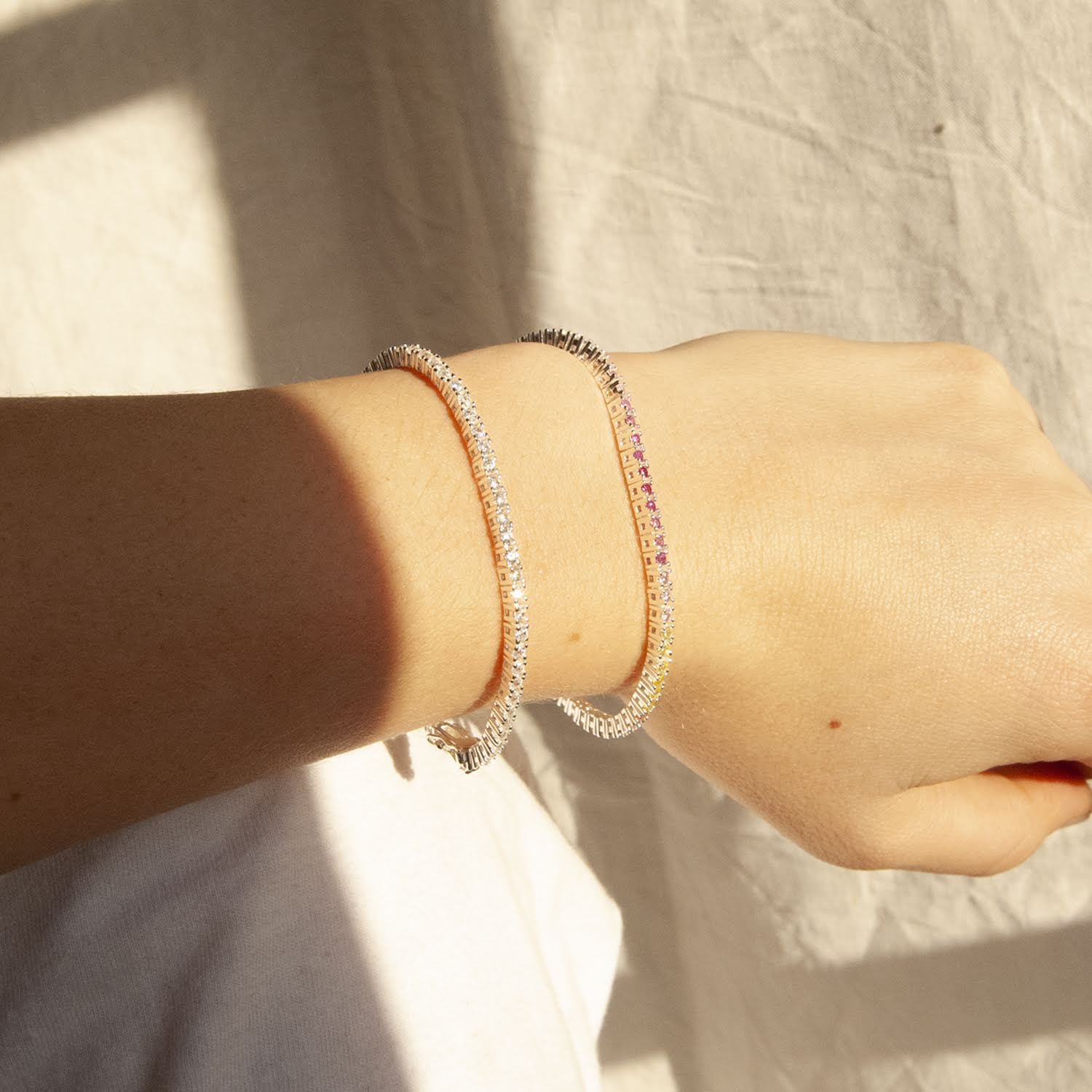 Close-up of a wrist wearing multiple bracelets on a neutral background - seolgold