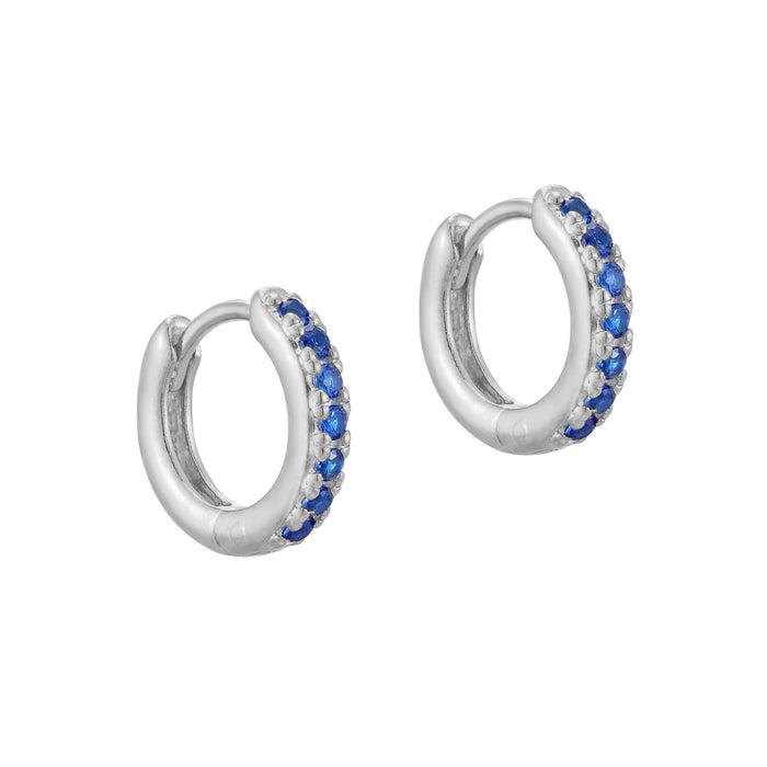 A pair of sterling silver huggie hoop earrings with blue cubic zirconia stones, displayed against a white background - seolgold
