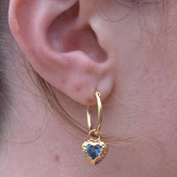 Gold hoop earring with a heart-shaped blue gemstone worn on an ear - seolgold