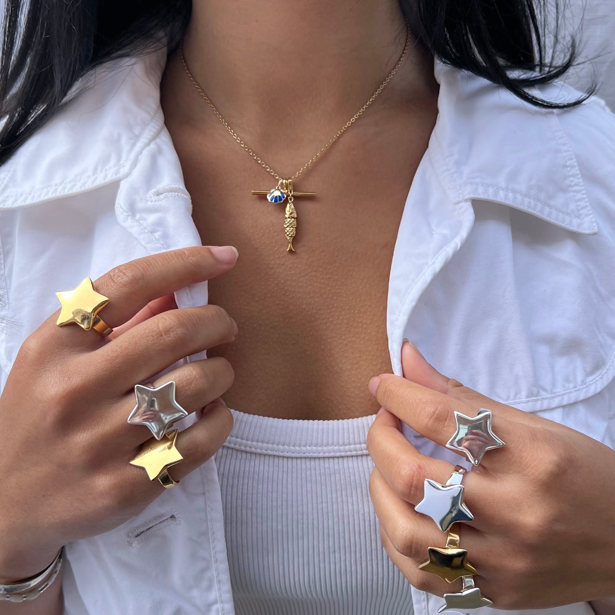 Person wearing a gold necklace with a pendant, holding star-shaped rings - seolgold
