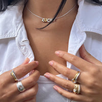 Close-up of a person wearing multiple rings on their fingers with a white jacket and necklace - seolgold