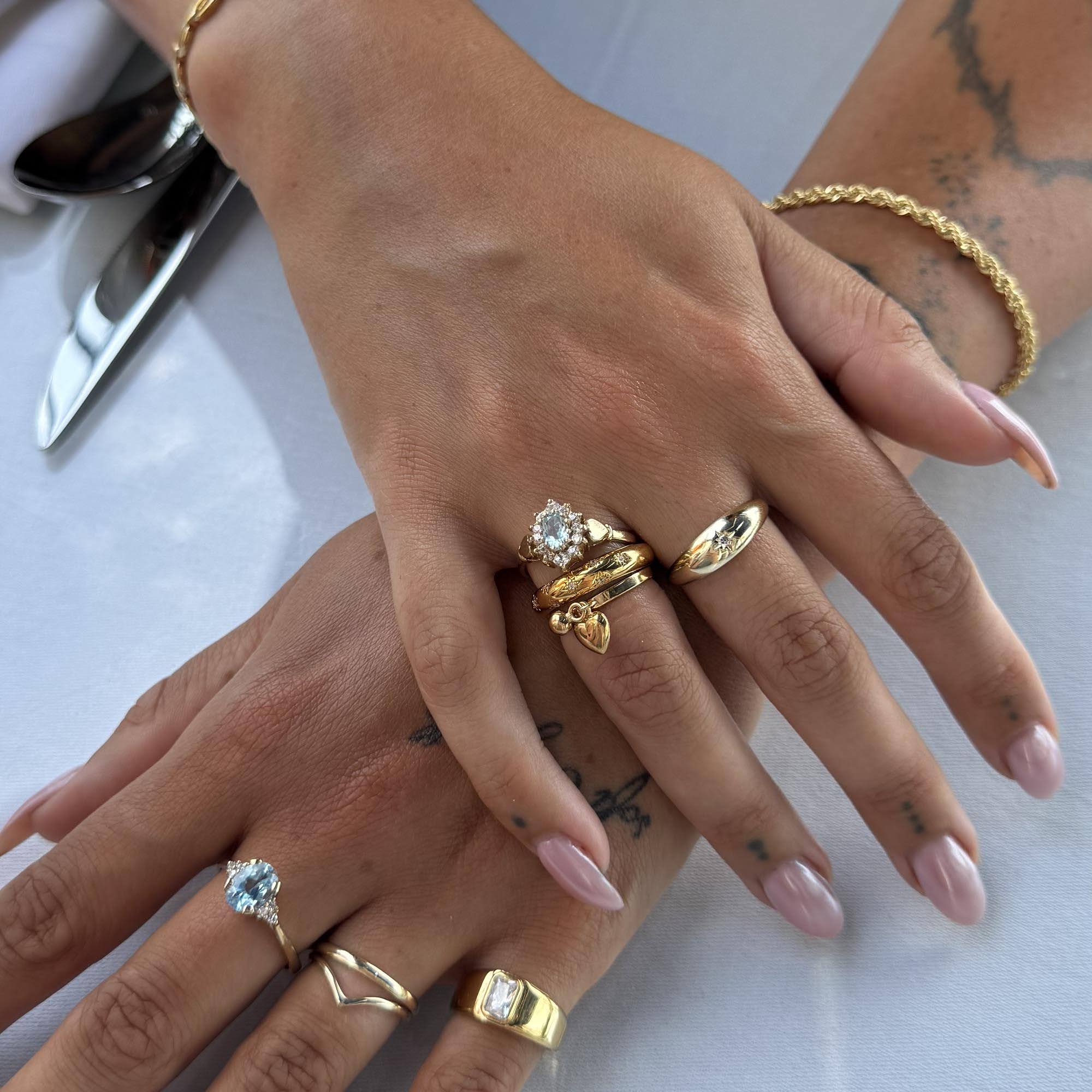 Close-up of a hand wearing multiple gold rings with gemstones on a white background - seolgold