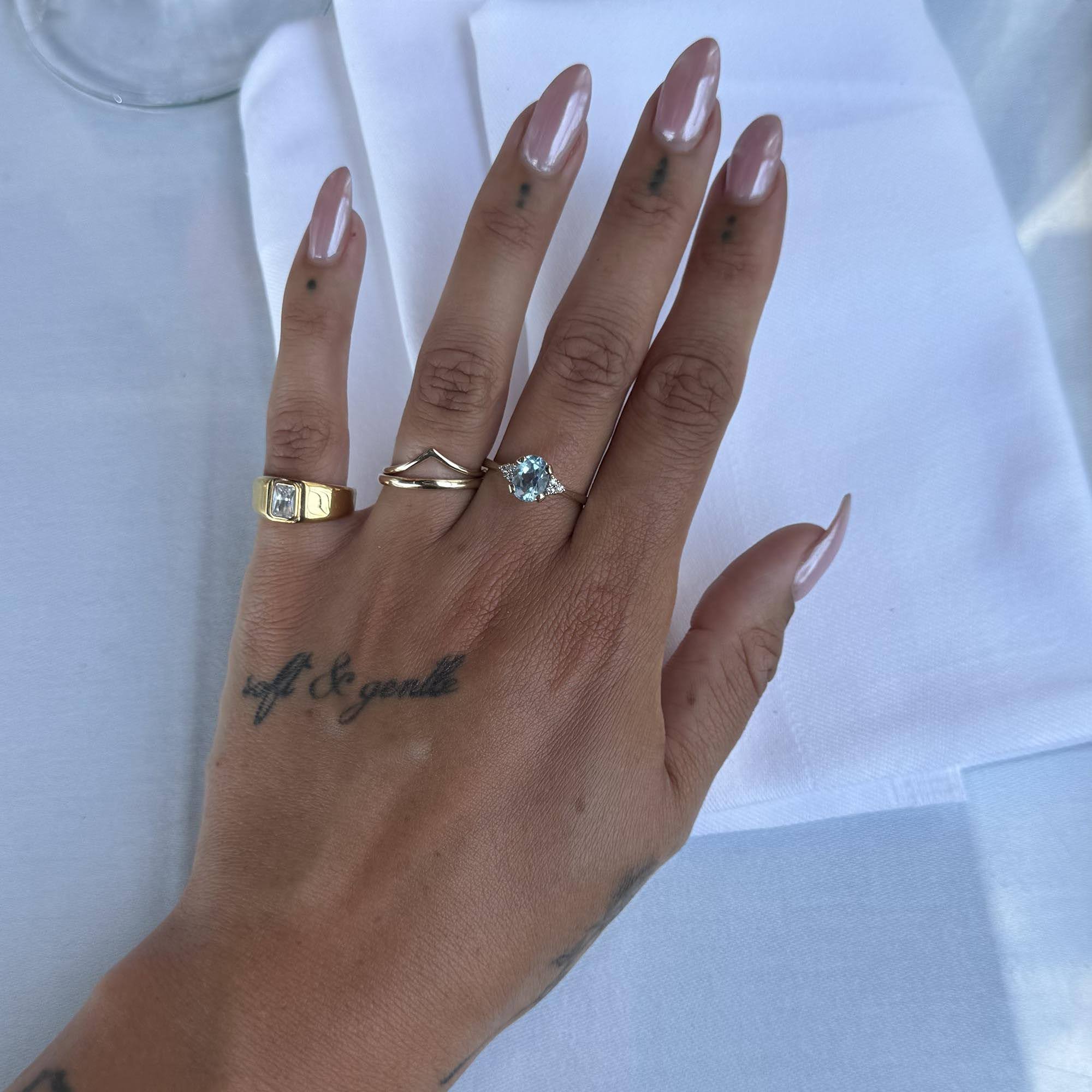 Hand wearing two gold rings with gemstones on a white background - seolgold