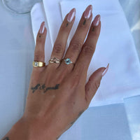 Hand wearing two gold rings with gemstones on a white background - seolgold