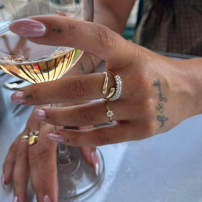 Hand with gold rings holding a glass of white wine - seolgold