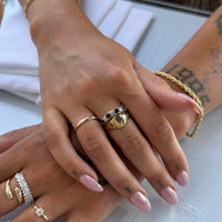 Close-up of hands with multiple gold rings on a light background - seolgold