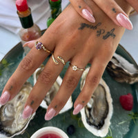Hand with gold rings and pink nail polish on a background of oysters and a bottle - seolgold
