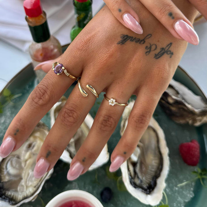 Hand with gold rings and pink nail polish on a background of oysters and a bottle - seolgold