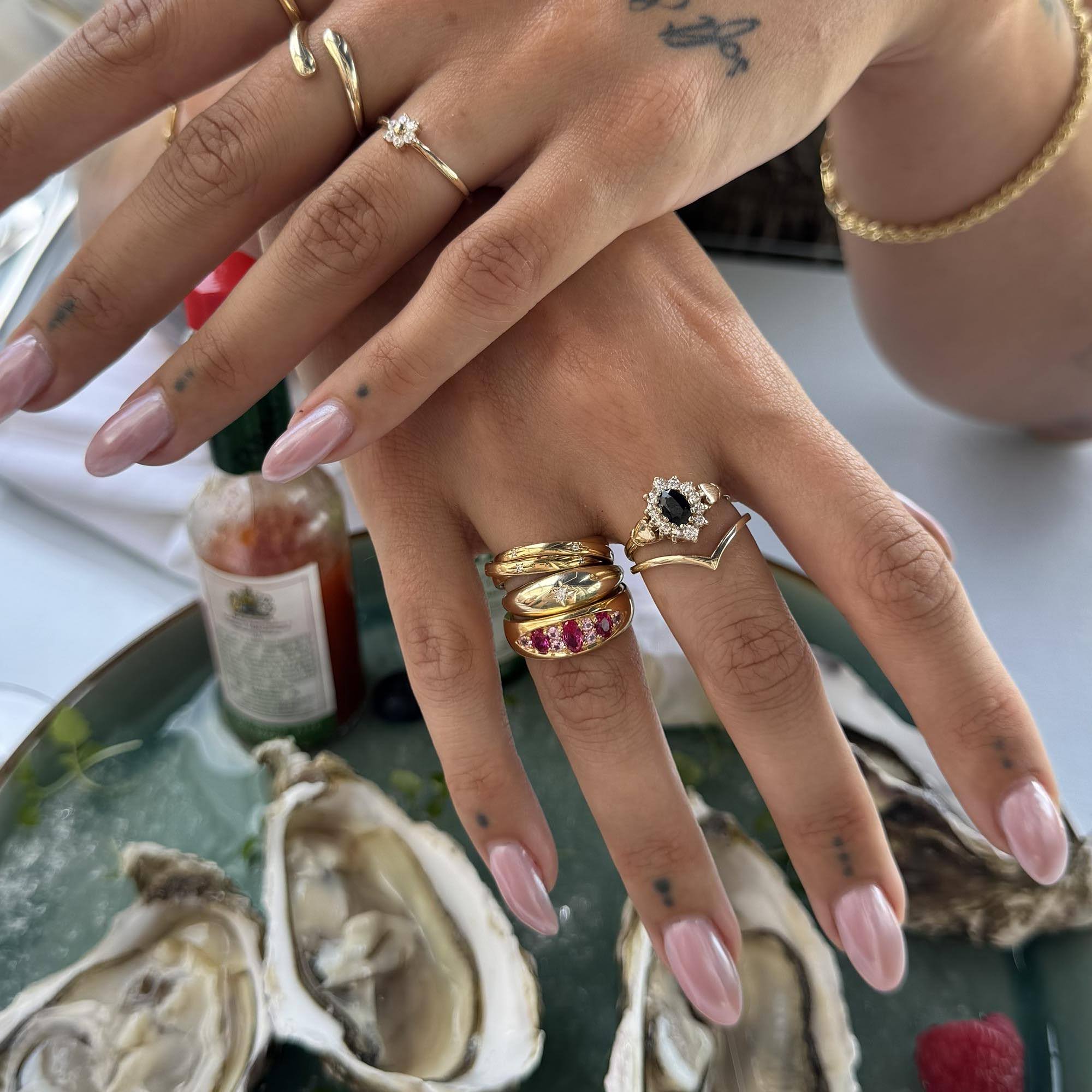Hand with multiple rings on a background of oysters and a glass of wine - seolgold