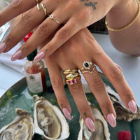 Hand with multiple rings on a background of oysters and a glass of wine - seolgold
