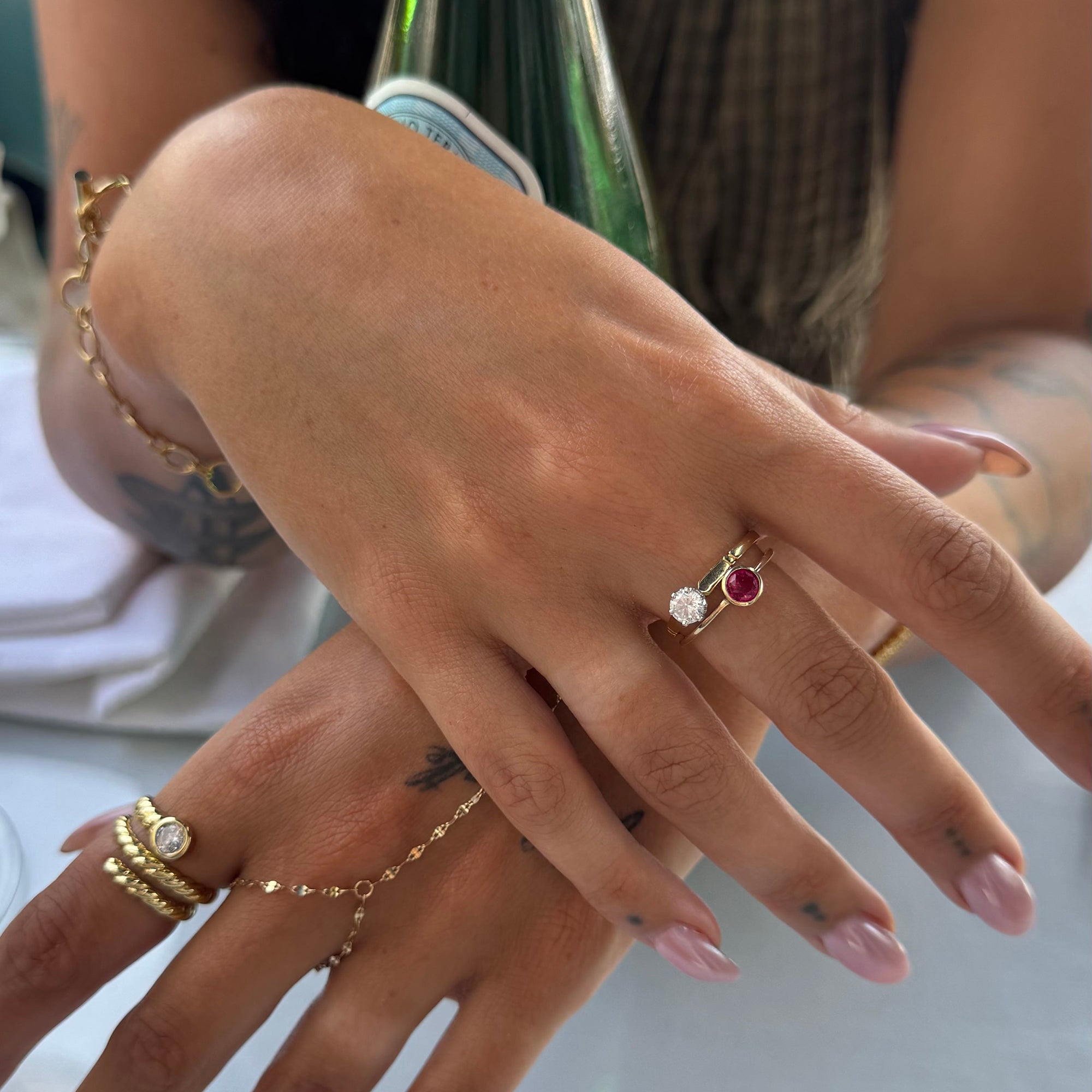 Close-up of a hand with multiple gold rings and a pinky ring on a blurred background - seolgold