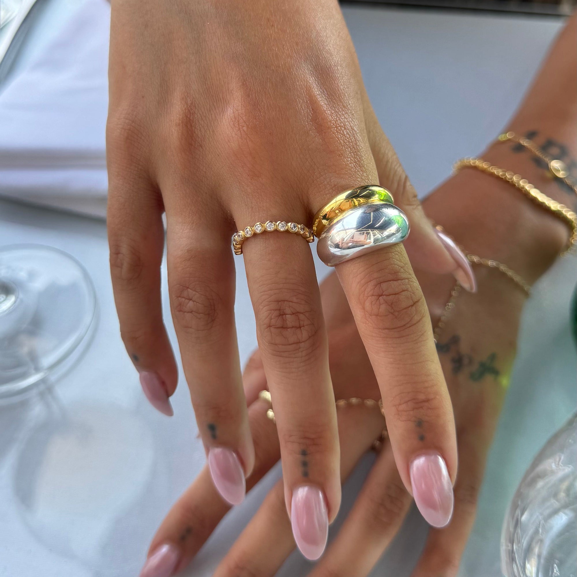 Hand wearing multiple rings with a blurred background - seolgold