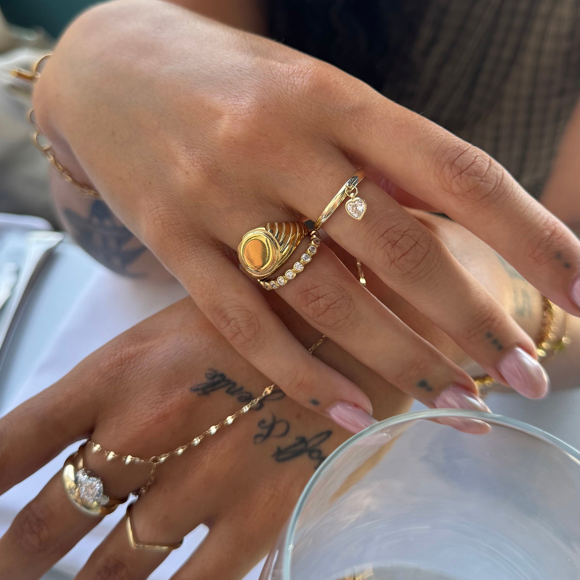 Close-up of a hand wearing multiple gold rings with a blurred background - seolgold