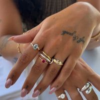 Close-up of a hand wearing multiple rings with visible tattoos - seolgold