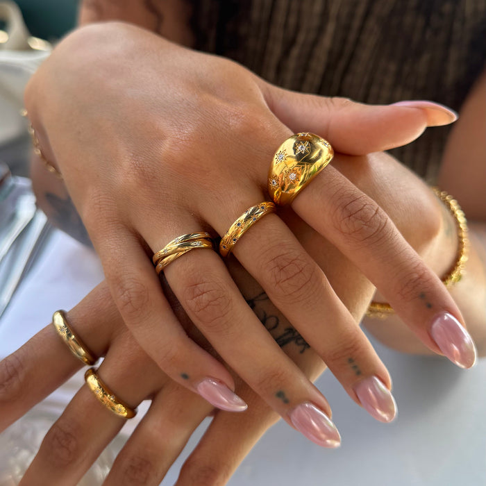 Close-up of a hand wearing multiple gold rings with a blurred background - seolgold