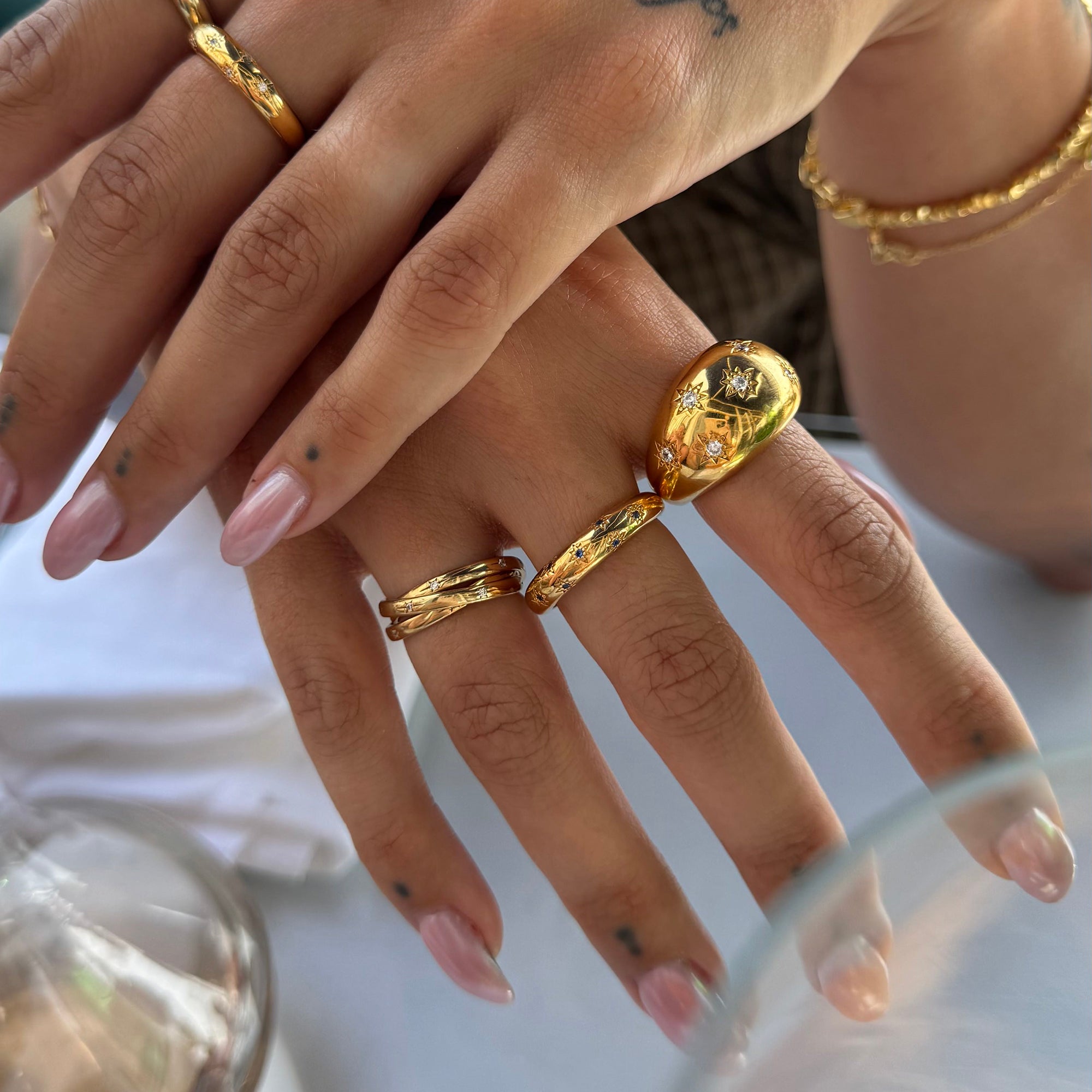 Close-up of a hand wearing multiple gold rings with a blurred background - seolgold