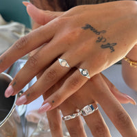 Close-up of a hand wearing multiple silver rings with a blurred background - seolgold