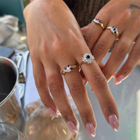Close-up of a hand wearing multiple rings with gemstones, blurred background - seolgold