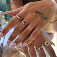Close-up of a hand wearing multiple rings with gemstones, set against a blurred background - Seolgold