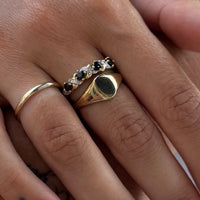 Close-up of fingers wearing gold rings with gemstones on a neutral background - seolgold