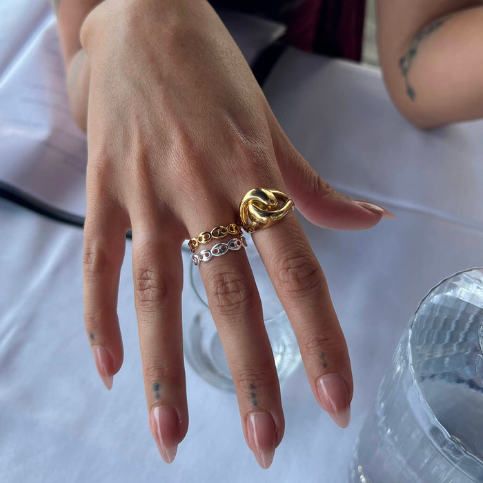 Hand wearing multiple gold rings on a blurred background - seolgold