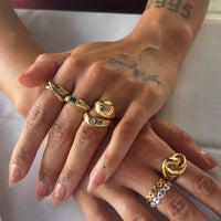 Close-up of hands wearing gold rings with a plain background - seolgold