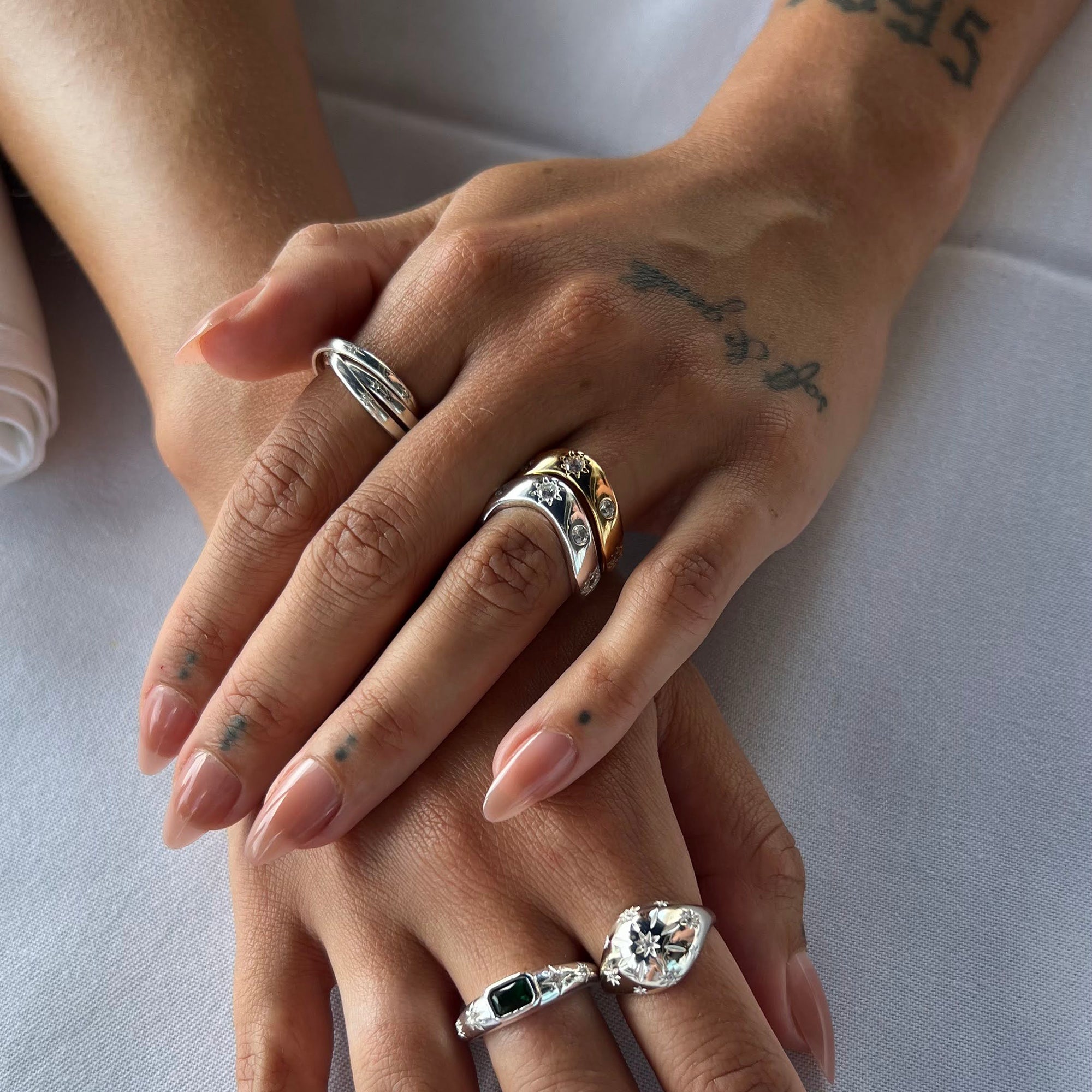 Close-up of hands with multiple rings on a light background - seolgold