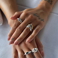 Close-up of hands with multiple rings on a light background - seolgold