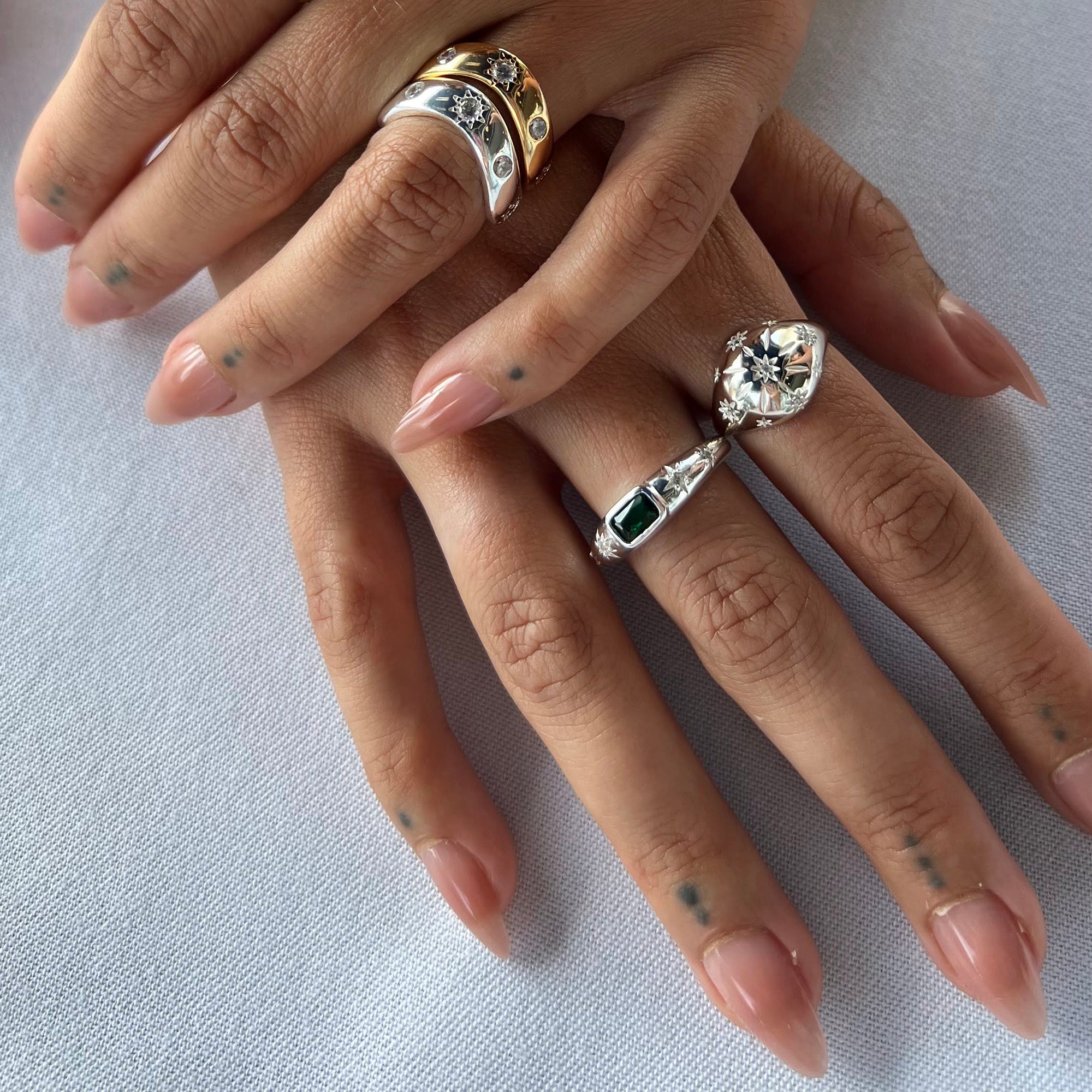 Close-up of a hand wearing two decorative rings on a light background - seolgold