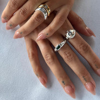 Close-up of a hand wearing two decorative rings on a light background - seolgold