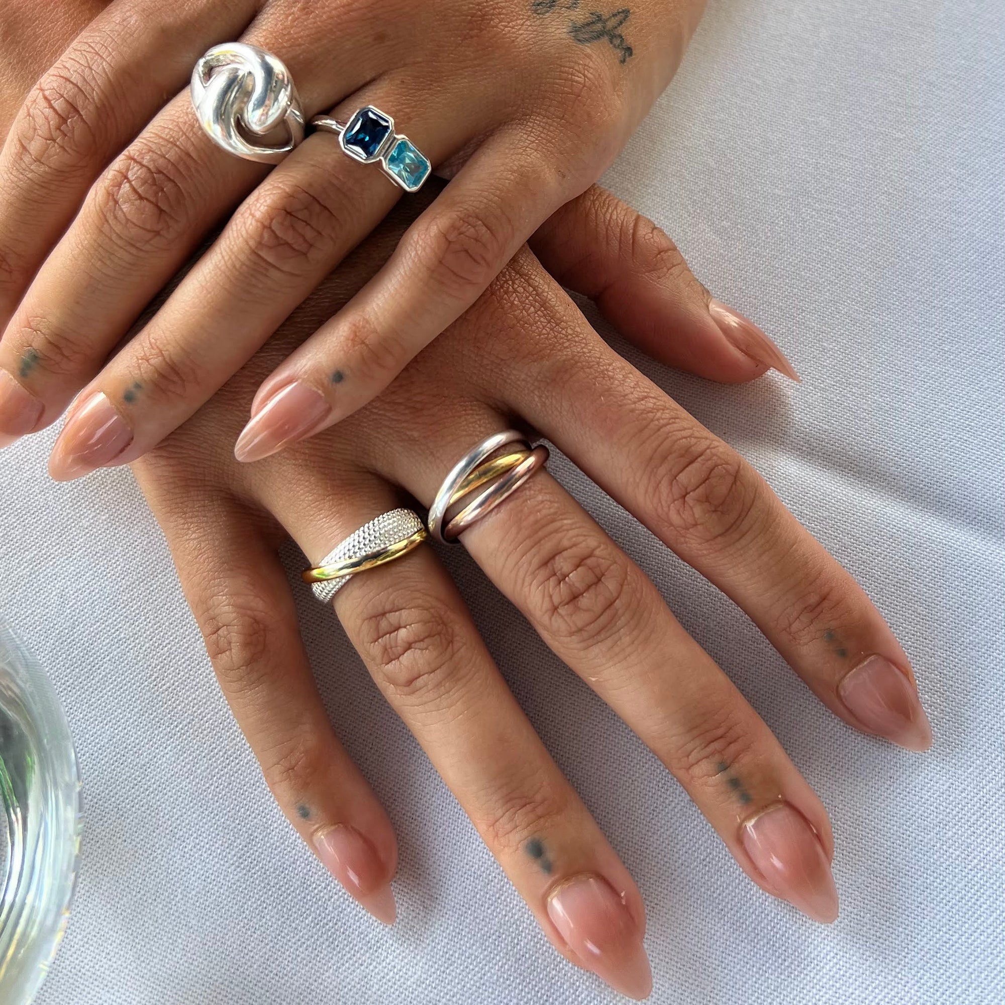 Close-up of hands with multiple rings on a white background - seolgold