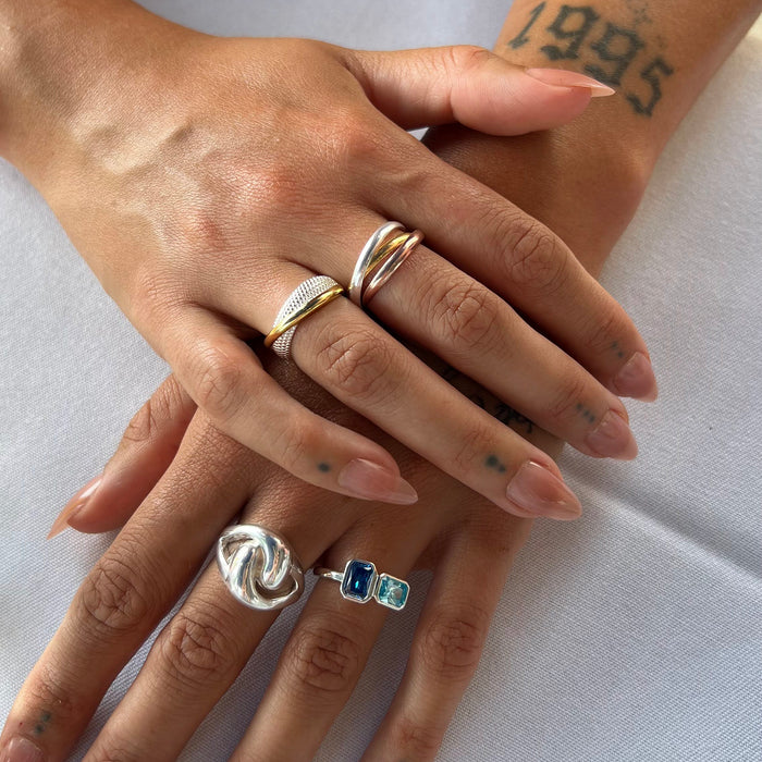 Close-up of hands wearing multiple rings on a light background - three metal trinity rolling ring - rose gold silver gold ring - seolgold