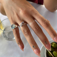 Hand wearing two silver rings with gemstones on a blurred background - seolgold