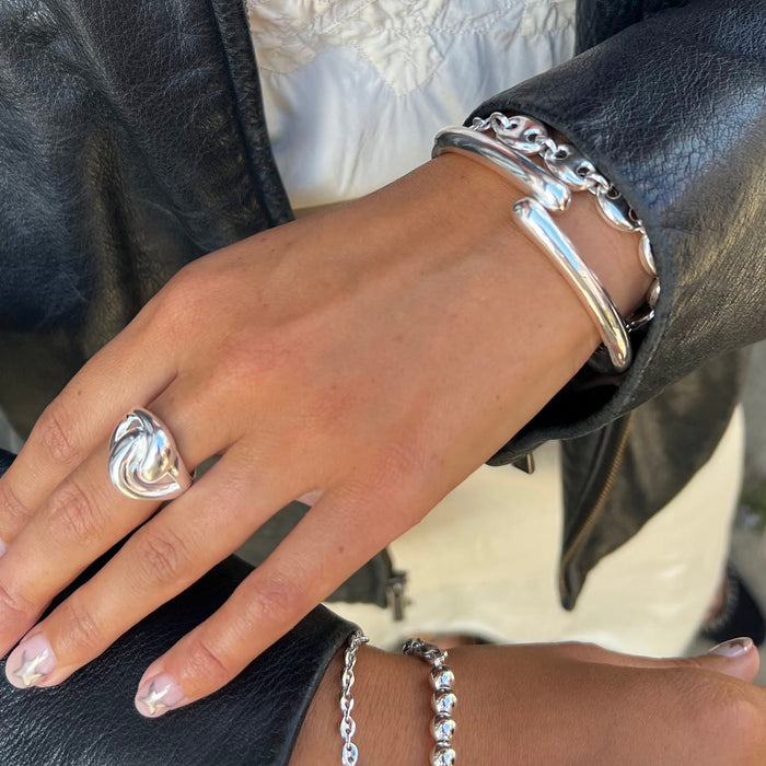 Hand wearing a silver ring and bracelets with a blurred background - seolgold