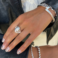 Hand wearing a silver ring and bracelet on a black leather surface - seolgold