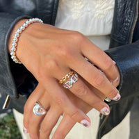 Close-up of a hand wearing multiple rings and a bracelet with a blurred background - seolgold