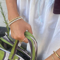 Hand holding a green bag strap with bracelets - seol gold
