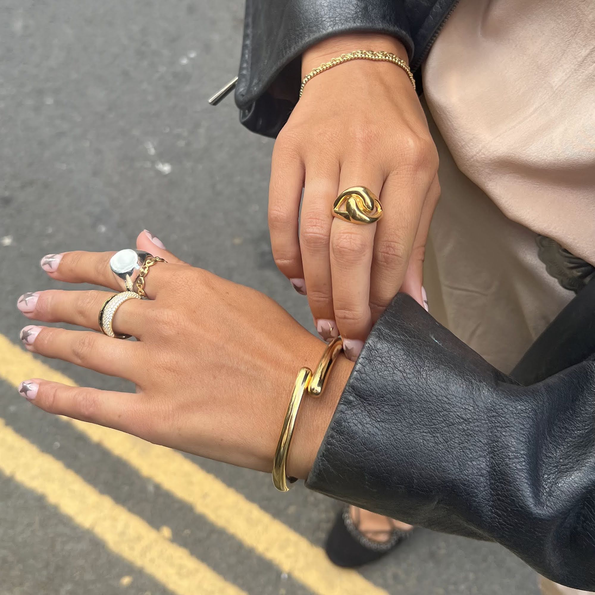 Close-up of two hands wearing gold jewelry on a street background - gold bangles - seolgold