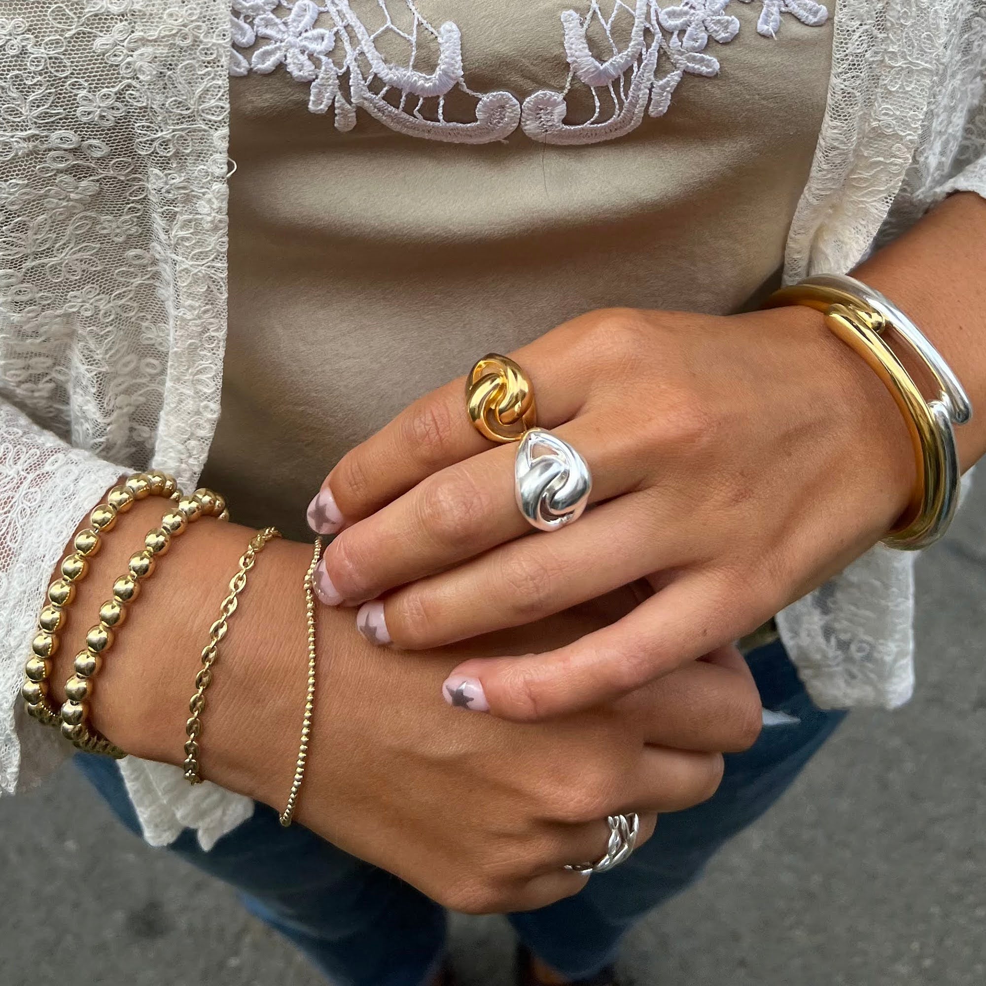 Close-up of hands wearing multiple gold and silver rings and bracelets.