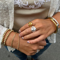 Close-up of hands wearing multiple gold and silver rings and bracelets.