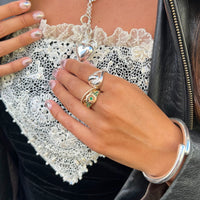Close-up of a hand wearing multiple rings with a lace garment in the background - seolgold